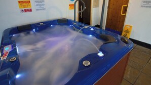 Una vasca idromassaggio con pannello di controllo, circondata da regolamenti e cartelli di avviso per la spa.