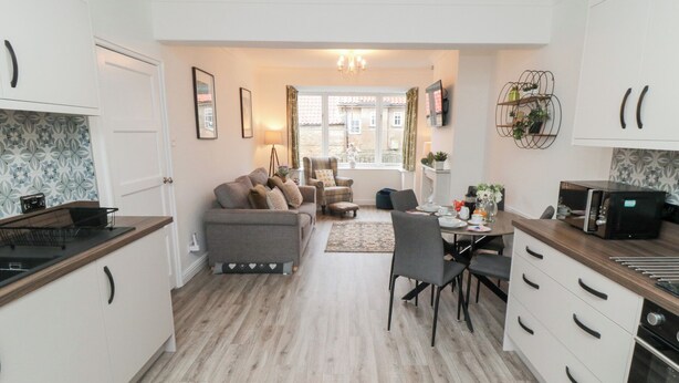 A modern kitchen with a dining area, featuring a sofa, chairs, and a table set for dining. - The Old Chapel (Scarborough)