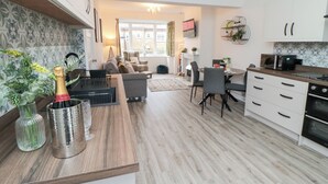 A modern kitchen with a dining area, wooden flooring, and a view of the outside. - The Old Chapel (Scarborough)
