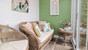 A cozy room with wicker furniture, a green wall, and a window with a white frame. - The Old Chapel (Scarborough)