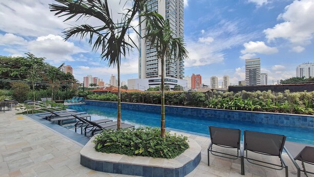 A rooftop pool with lounge chairs, surrounded by greenery and tall buildings in the background. - Extension Berrini (Sao Paulo)