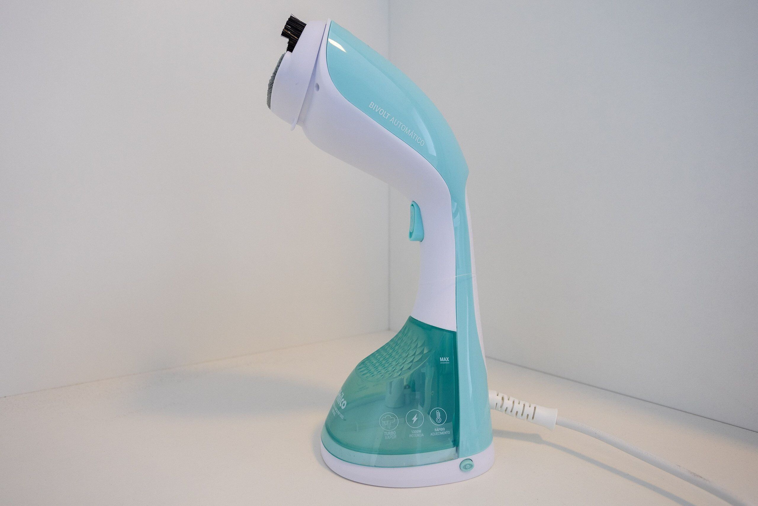 A hair dryer with a white and teal color scheme, labeled "BIVOLT AUTOMATIC," and a power cord.