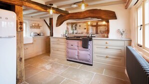 A kitchen with exposed wooden beams, a vintage stove, and a stone-tiled floor.
