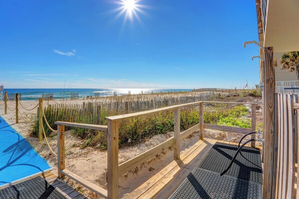 A wooden deck with a view of the beach and ocean.