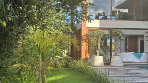 A modern house with a well-maintained garden, large windows, and a visible outdoor seating area.
