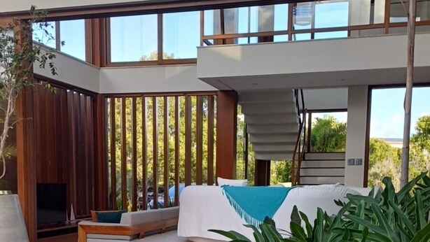 A modern pool area with a clear view of the pool, a lounge with seating, and a staircase leading to an upper level.