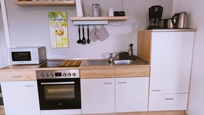 Une cuisine compacte équipée d’un four à micro-ondes, d’un four, d’un évier et d’un plan de travail en bois.