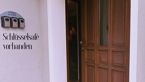 L’entrée d’un hôtel, avec une porte en bois, un panneau indiquant la présence d’un coffre-fort pour les clés, et un appareil fixé au mur permettant d’accéder aux chambres.