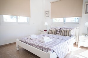 Une chambre à coucher comprenant un lit, deux tables de chevet, une commode, une lampe et une fenêtre donnant sur un beau paysage.