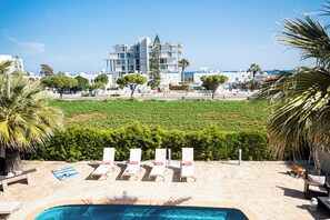 A pool area with lounge chairs and a view of a modern building in the background.