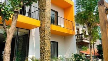 A modern building with a white facade, yellow balconies, and a stone pillar.