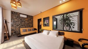 Un dormitorio moderno con una cama grande, una pared de acento de piedra, un sofá, una escalera de madera y una ventana grande con vistas a una planta.