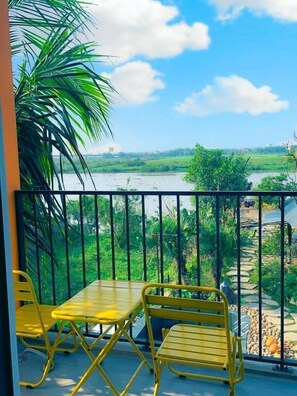 A balcony with yellow metal furniture, a view of a river, and greenery. - Trang An Cozy House (Tay Hoa Lu)