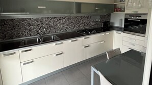 A modern kitchen with white cabinets, a black countertop, and a tiled backsplash. - Trilo Rho Fiera Milano House Rino Palmanova 12 (Rho)