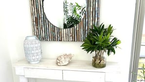 A white console table with a rustic mirror, decorative items, and potted plants. - Villa Koki Bonheur, house Plain Pied- 700m Plage Pointe aux canonniers (Grand Baie)