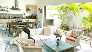 A modern kitchen with a dining area, wicker furniture, and a view of tropical plants. - Villa Koki Bonheur, house Plain Pied- 700m Plage Pointe aux canonniers (Grand Baie)