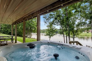 Una vasca idromassaggio con un pontile in legno e vista su un lago.