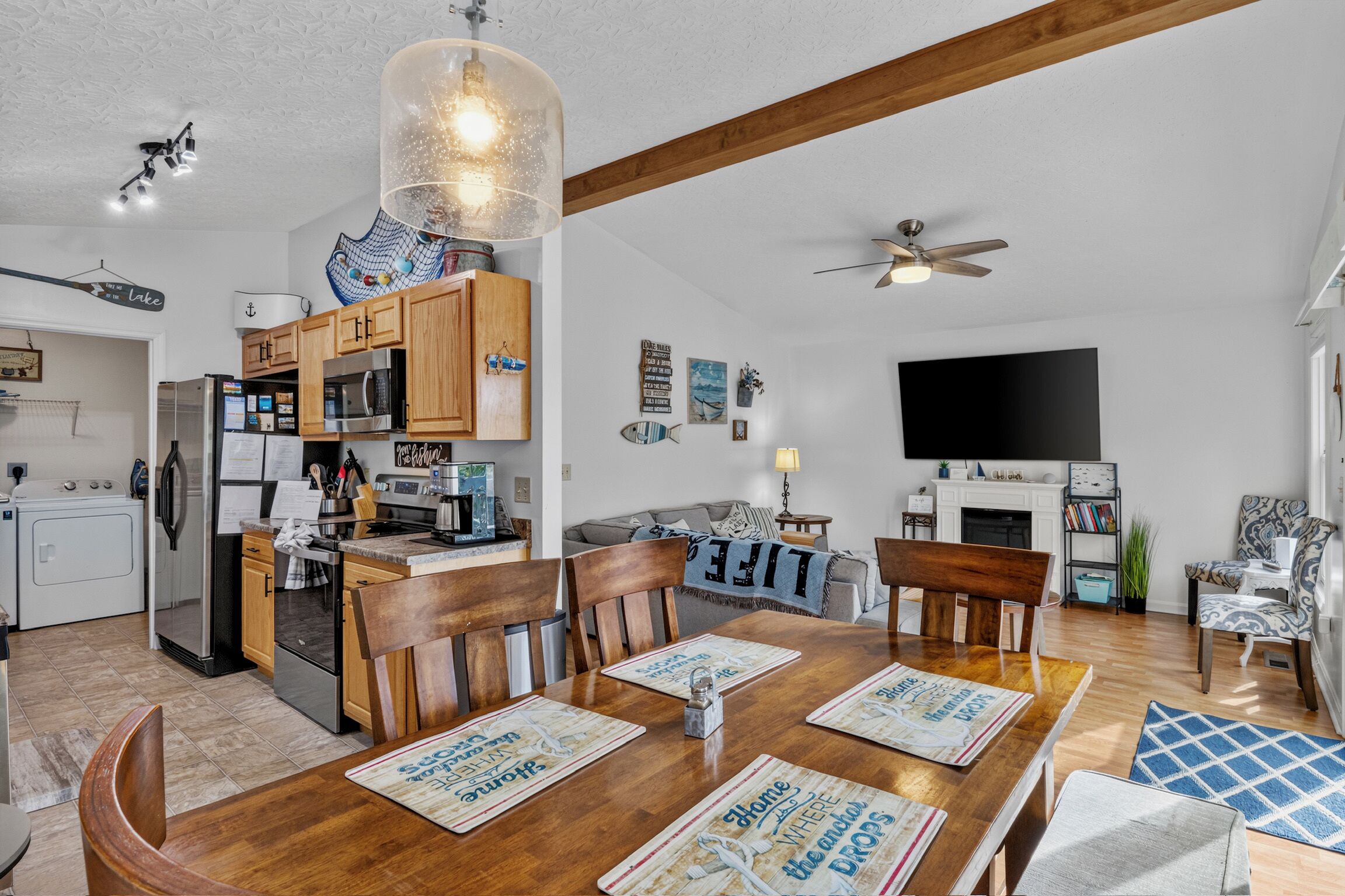 Une cuisine moderne avec des meubles en bois, des appareils électroménagers en acier inoxydable et un coin repas doté de tables et de chaises en bois.