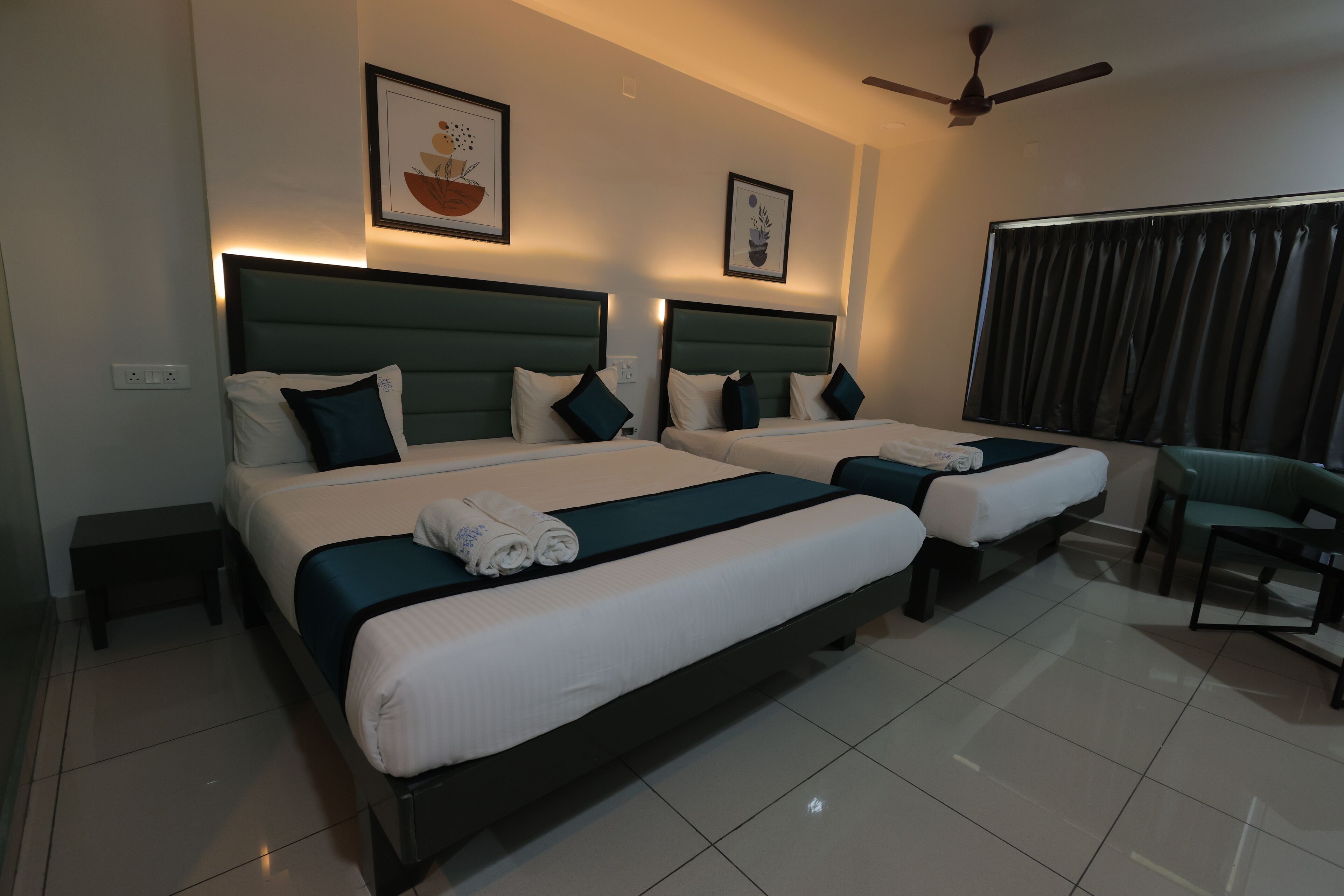 A hotel room with two beds, a ceiling fan, and a view of the outdoors.