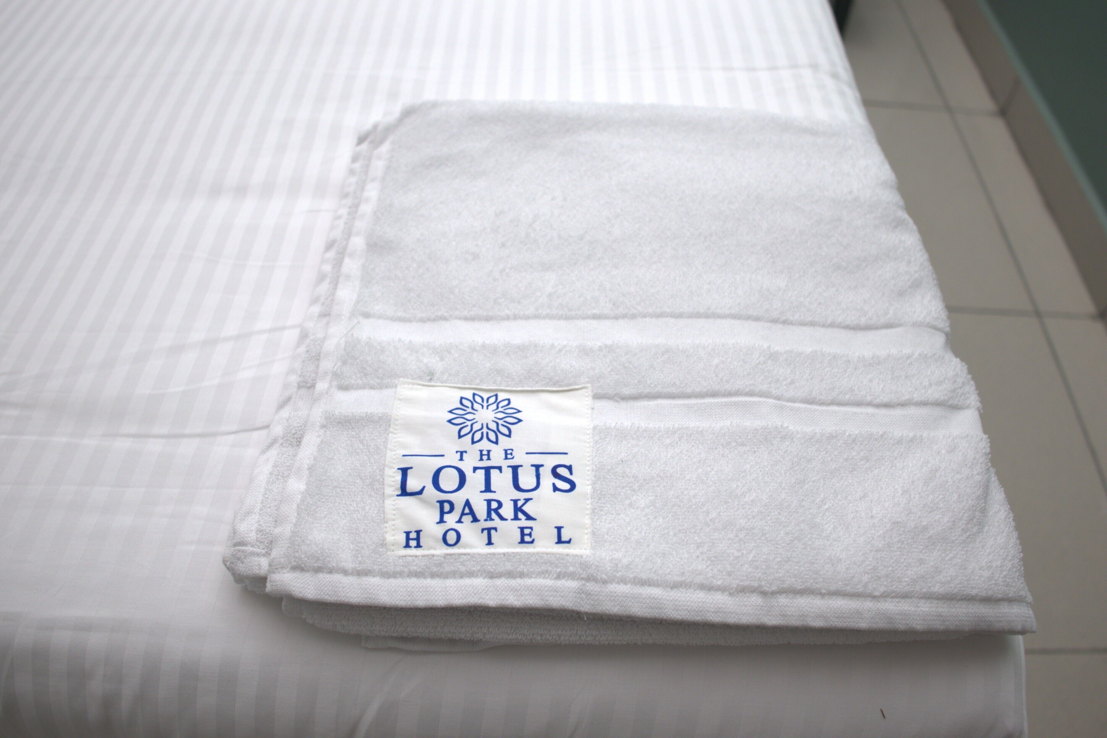A neatly folded white towel with a label from The Lotus Park Hotel.