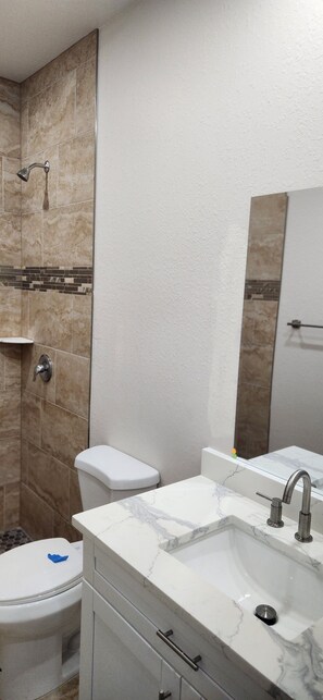 Une salle de bain avec un lavabo en marbre, des toilettes et un espace douche.