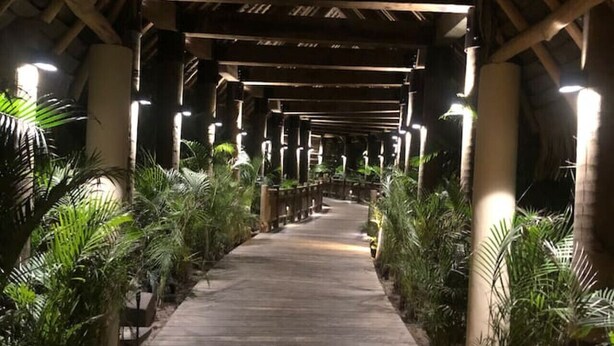 A wooden pathway flanked by potted plants under a covered structure with a peaked roof. - Refined Condo w/ Vidanta Access (Nuevo Vallarta)