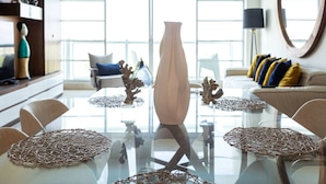 A modern dining area with a glass table, clear glassware, and decorative coral pieces. - Refined Condo w/ Vidanta Access (Nuevo Vallarta)