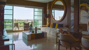 A spacious living room with a large window, a round mirror, and a view of greenery outside. - Refined Condo w/ Vidanta Access (Nuevo Vallarta)