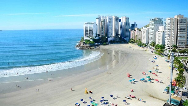 Une plage bordée d’immeubles de grande hauteur, une étendue de sable et de nombreux parasols.
