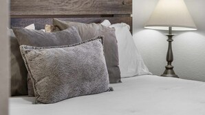 En seng med puder, en lampe og et trægavl.