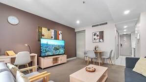 Ein modernes Wohnzimmer mit Fernseher, Sitzecke und Kunstwerken an den Wänden.