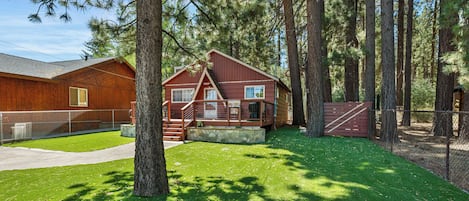 A cabin with a stone foundation, wooden exterior, and a porch with a railing.