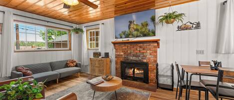 Una sala de estar acogedora con chimenea, techo de madera y un comedor.
