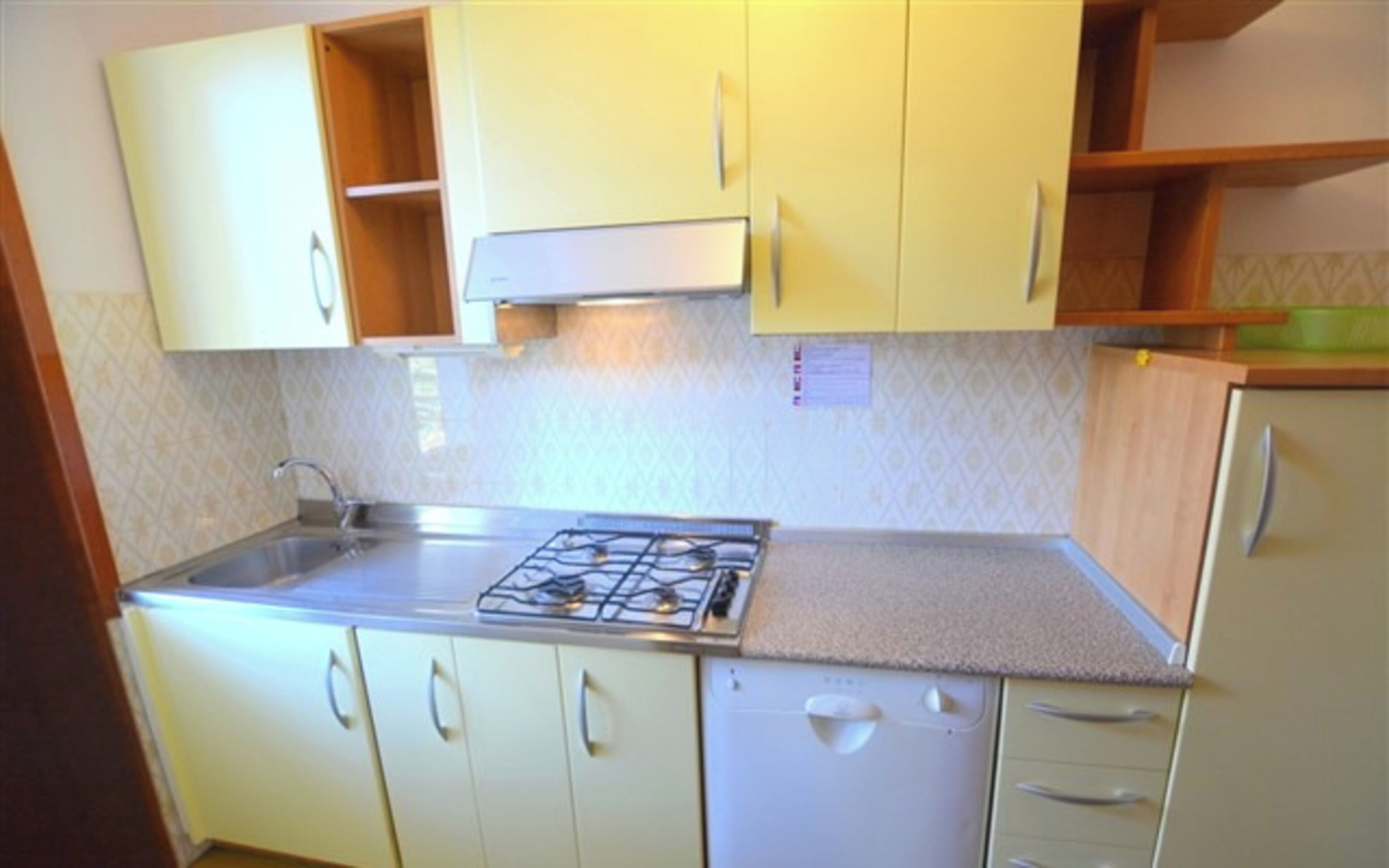 Una cocina compacta con estufa a gas, lavamanos y refrigerador.