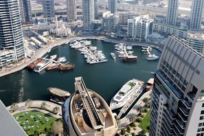 A marina with multiple boats docked, surrounded by high-rise buildings and a prominent curved structure in the foreground.
