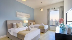 A hotel room with two beds, a city view, a desk with a vase, and a painting on the wall. - Livbnb High Floor 2B  Marina View | Walk to Beach (Dubai)