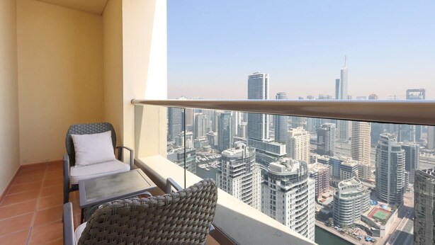 A balcony with a view of a cityscape, a chair, and a small table. - Livbnb High Floor 2B  Marina View | Walk to Beach (Dubai)