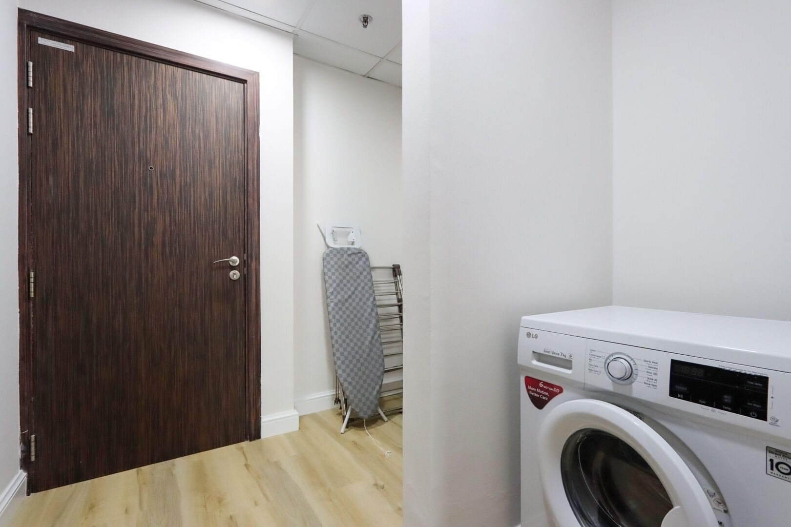 Une buanderie équipée d’un lave-linge, d’un étendoir et d’une porte en bois.
