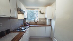 A compact kitchen with white cabinets, a gas stove, and a window with a view of trees. - 1 Bed-park View-balcony-wifi-pet Friendly (London)