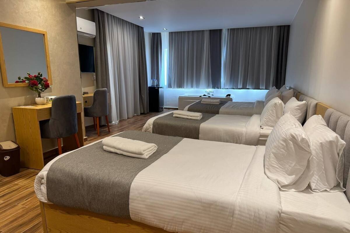 A hotel room with two beds, a desk, a chair, and a mirror.