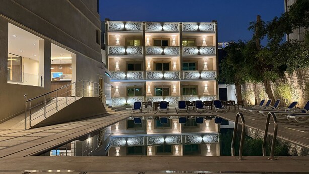 A hotel with a pool area, outdoor seating, and a staircase leading to the entrance. - Dyafa Pyramids Hotel & Spa (Giza)