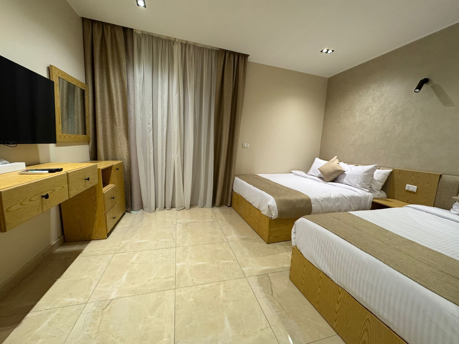 A hotel room with a bed, a desk, a chair, and a television.