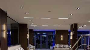 A spacious lobby with a polished marble floor, two sofas with cushions, a staircase, and a glass entrance leading to a dimly lit interior. - Dyafa Pyramids Hotel & Spa (Giza)