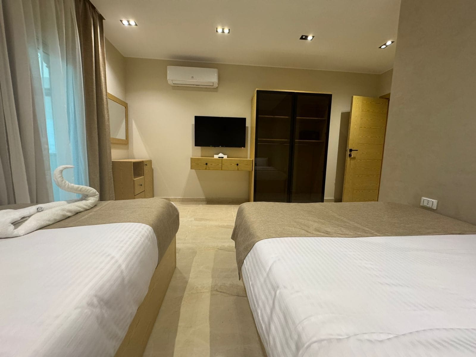Habitación de hotel con dos camas, televisor de pantalla plana, armario y baño.