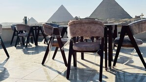 A rooftop terrace with modern chairs and tables, offering a view of the pyramids. - Dyafa Pyramids Hotel & Spa (Giza)