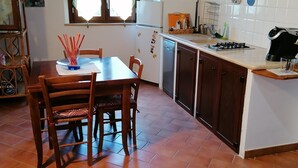 A kitchen with a dining table, chairs, a refrigerator, a stove, and a window.