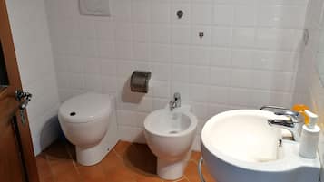 Une salle de bain équipée de toilettes, d’un bidet et d’un lavabo.