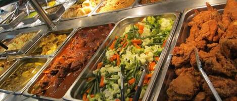 Un buffet proposant une variété de plats, notamment des salades, de la viande et des légumes.