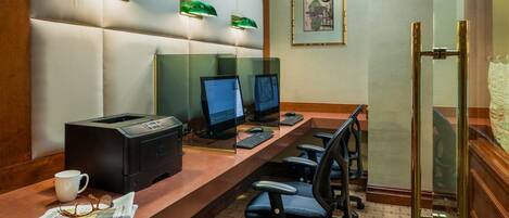 Habitación de hotel con un escritorio grande, dos computadoras, una impresora y dos sillas.