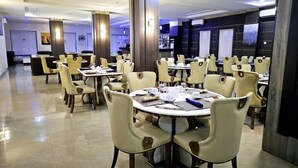 A modern dining area with round tables and beige chairs, featuring a clean, polished floor and a neutral color palette. - Carlton Swiss Luxury Residency (Abuja)